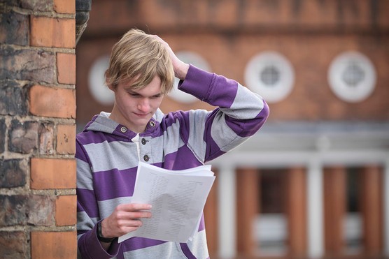 teenage boy collecting his exam results and looking worried and anxious