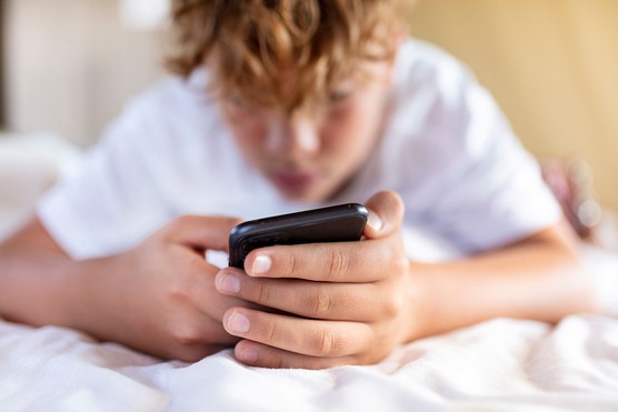 teenage boy scrolling social media on smartphone at home close up