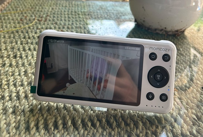 Close-up of Momcozy 5-Inch Dual-Mode Smart Baby Monitor parent unit on garden table