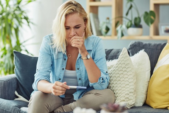 Shot of a young woman taking a pregnancy test at home and looking worried