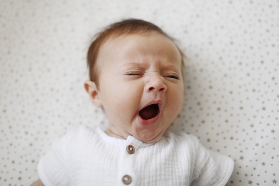 baby lying in cot and yawning