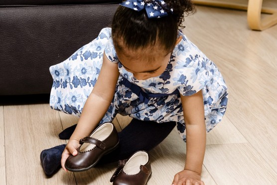 little girl arranging her shoes in front of her so she can put them on