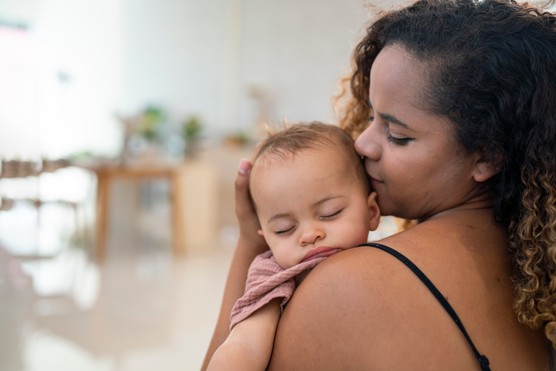 Close Up Of Mother Cuddling Sleeping Baby Daughter At Home