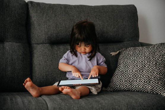 Little girl playing video games on digital tablet.