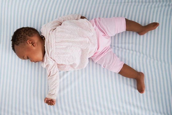 Overhead Shot Of Baby Girl Sleeping In Nursery Cot