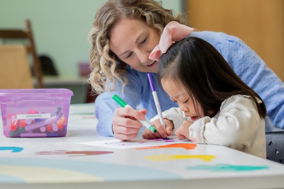 Special education teacher assists student with Down Syndrome who is working on assignment