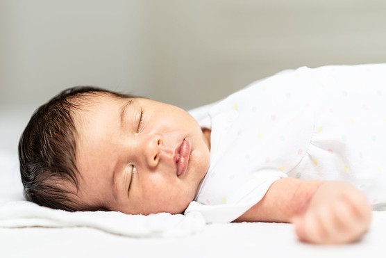 Close-up of a newborn baby girl peacefully sleeping in the crib.