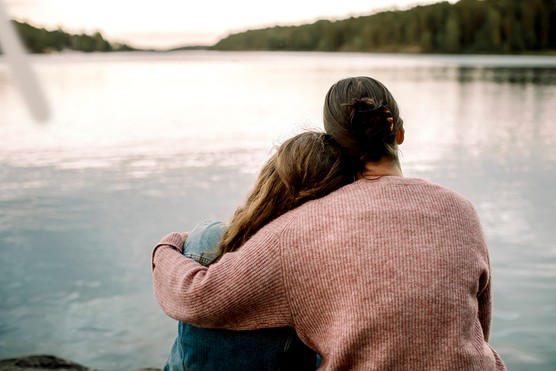 mother and daughter sitting together by a lake