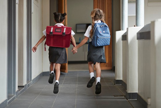 two girls at school running down the corridor together