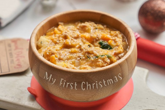 Annabel Karmel's Turkey Dinner Puree for babies served in a bowl with Christmas decorations in the background