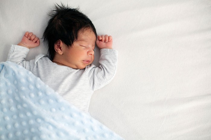 unusual-baby-boy-names baby boy lying on a white sheet with blue blanket