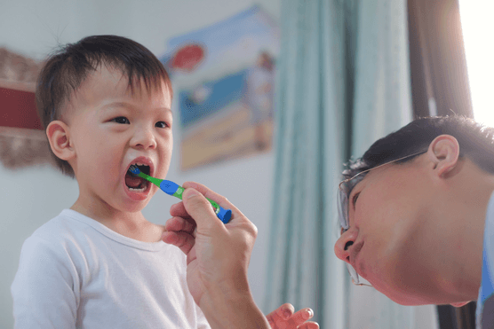 little boy with parent brushing his teeth