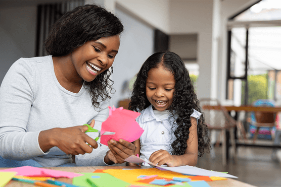 Mother and child smiling as they craft at a table at home